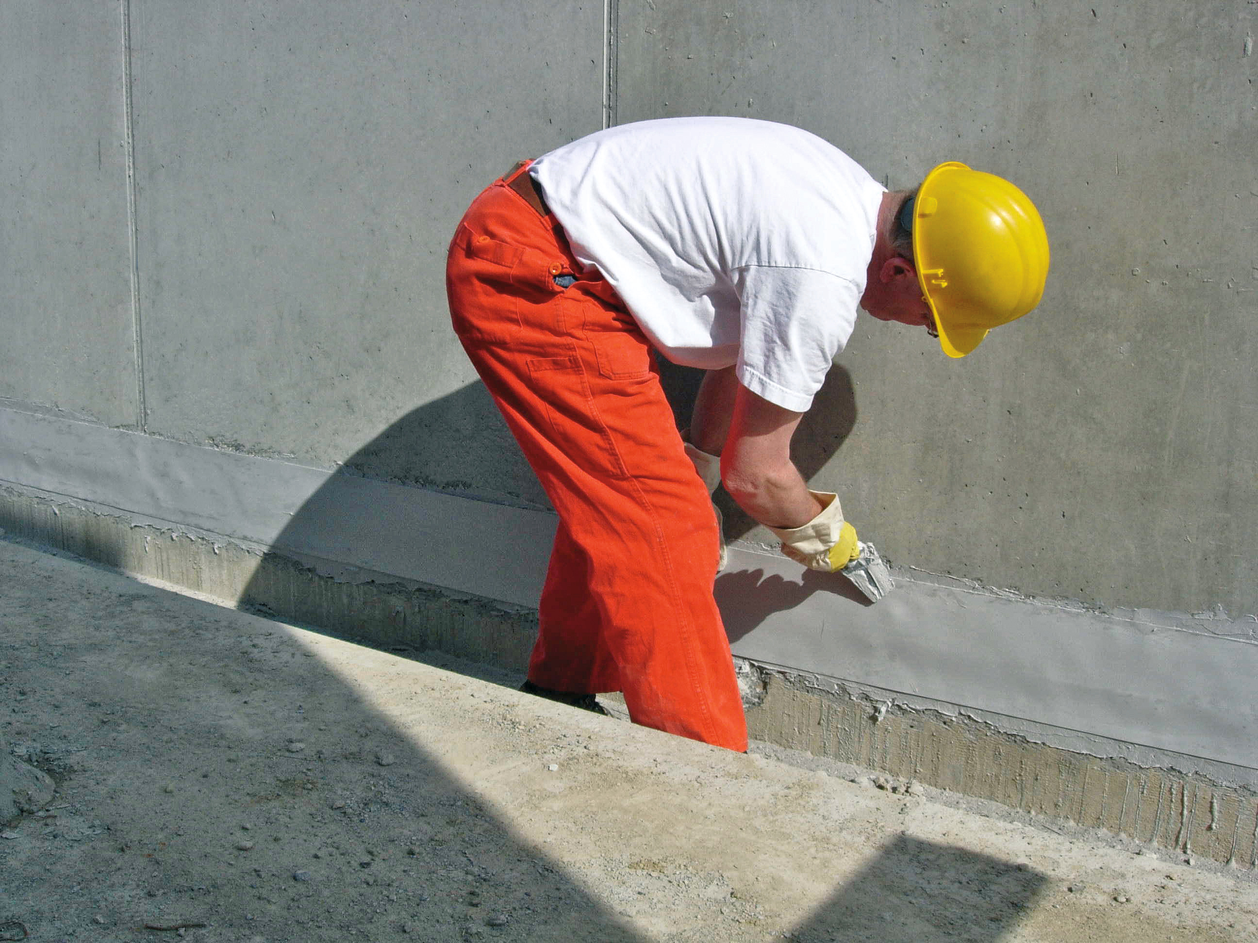 Application of Sikadur-Combiflex® to joint in concrete Male applicator applying Sikadur Combiflex to joint in concrete facade of building with hand trowel