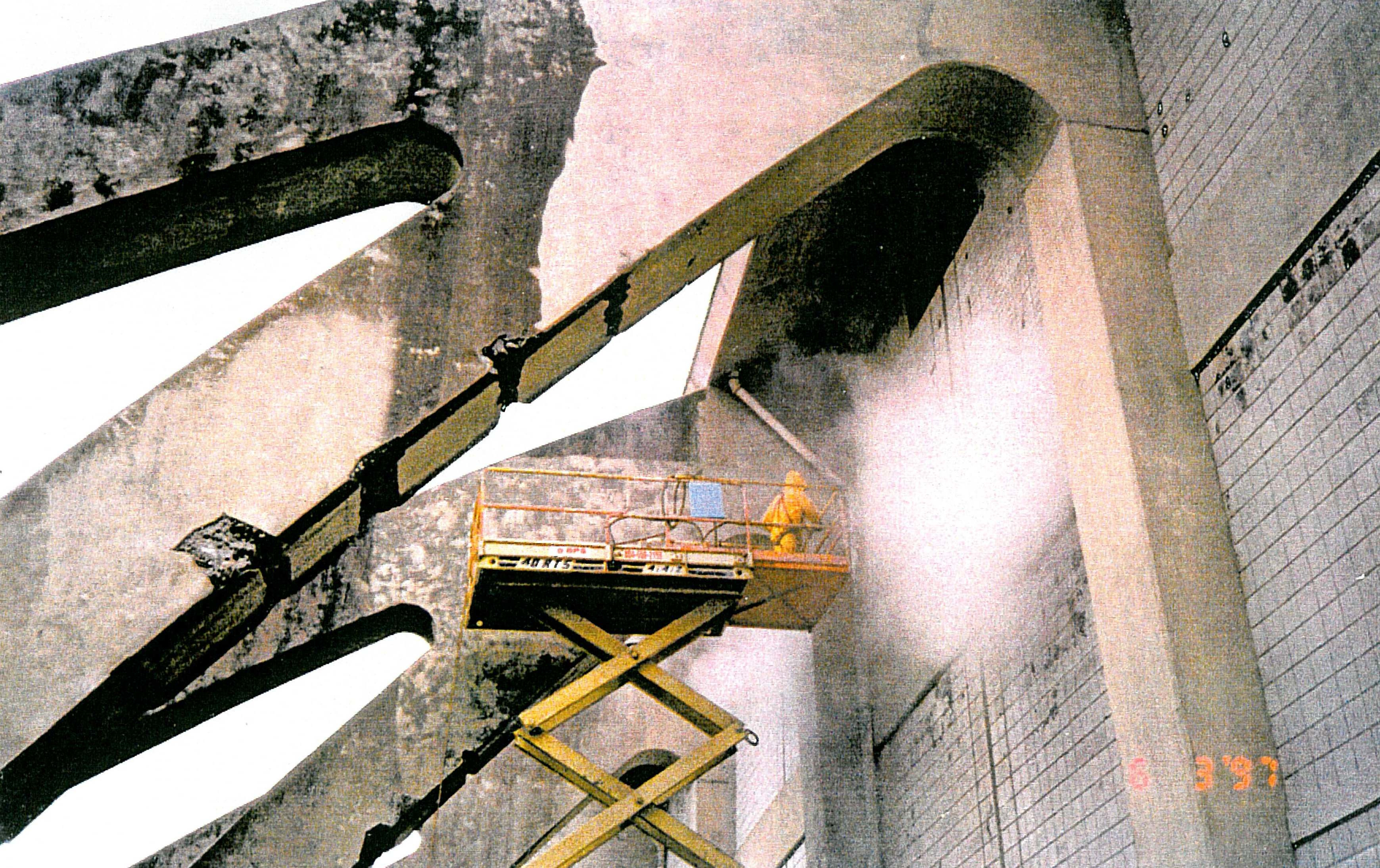 Cassell Coliseum sport center buttress structure during concrete repair renovation with worker on scaffold